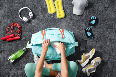 Photo of Woman with bag and sports items on grey carpet, top view