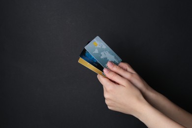 Photo of Woman holding credit cards on black background, closeup