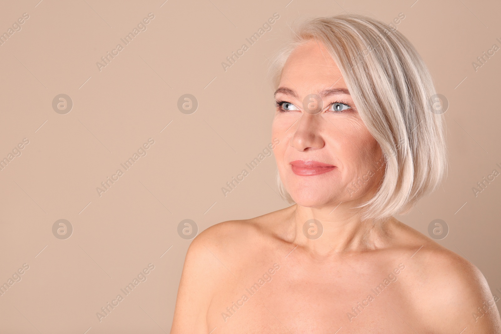 Photo of Portrait of charming mature woman with healthy beautiful face skin and natural makeup on beige background, space for text