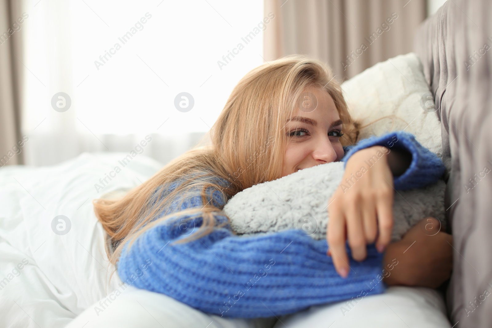 Photo of Beautiful young woman lying in bed with pillows at home. Winter atmosphere