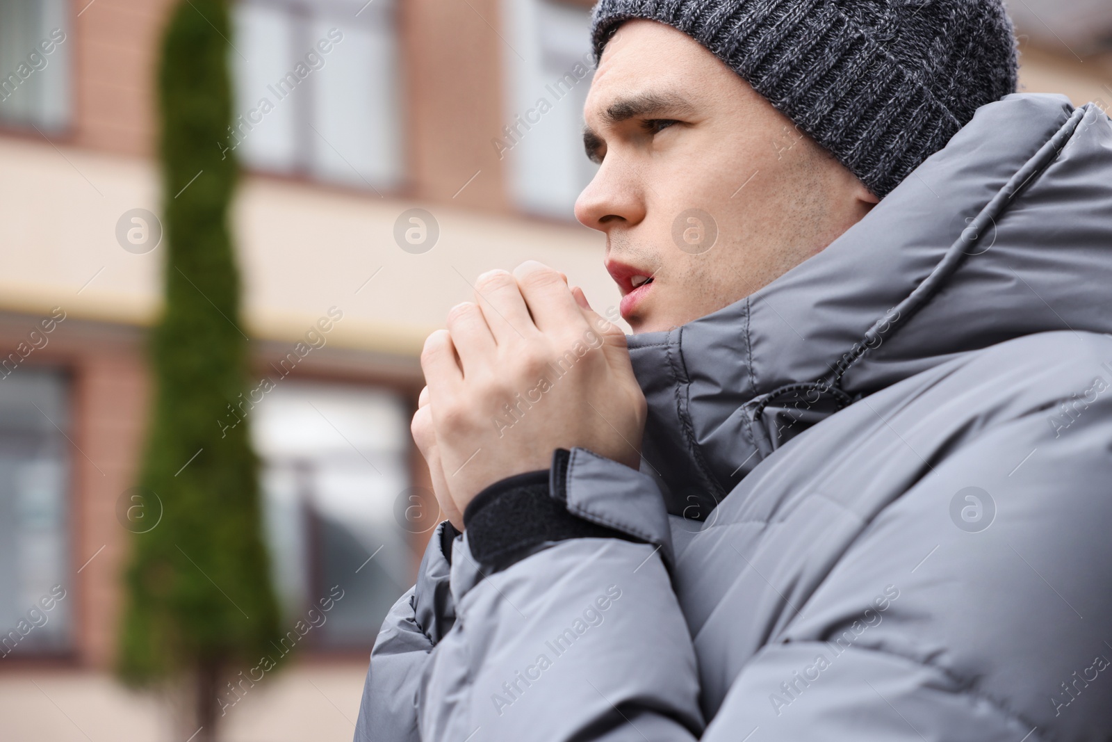 Photo of Sick young man coughing on city street. Cold symptoms