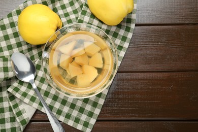 Delicious quince drink in glass bowl, fresh fruits and spoon on wooden table, top view. Space for text