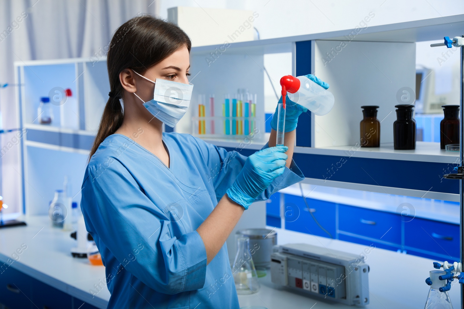 Photo of Scientist pouring liquid into test tube indoors. Laboratory analysis