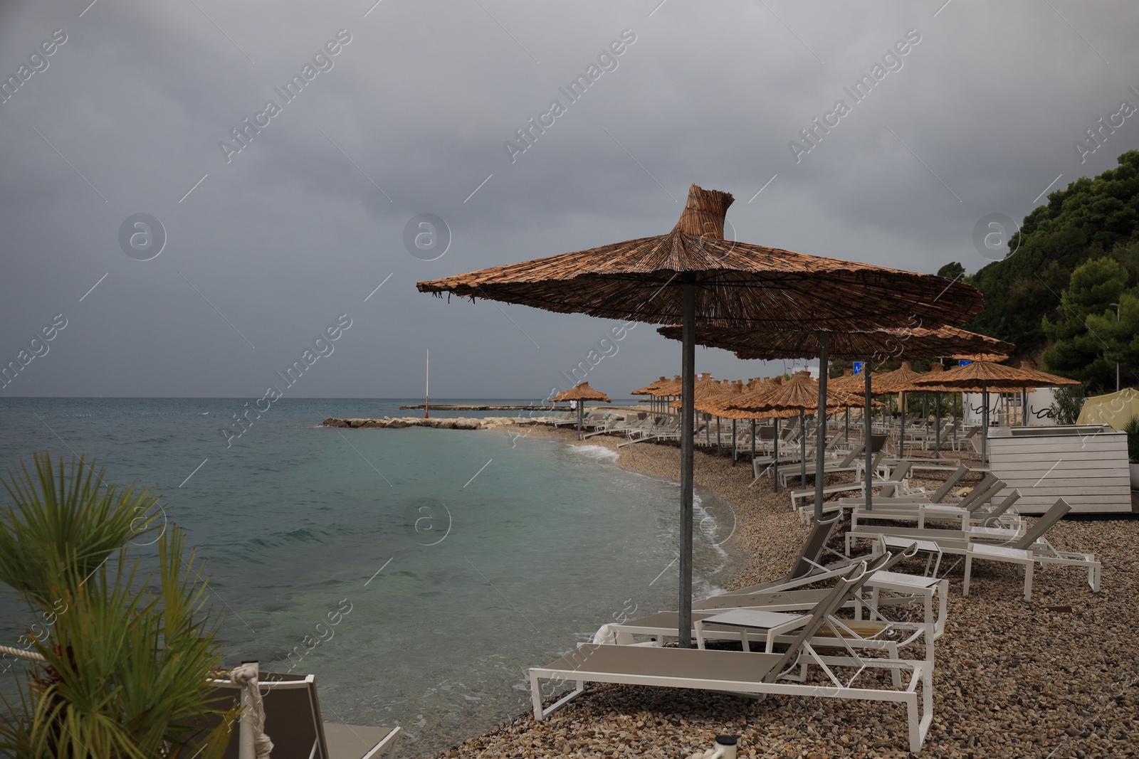 Photo of Beautiful straw umbrellas and sunbeds near sea