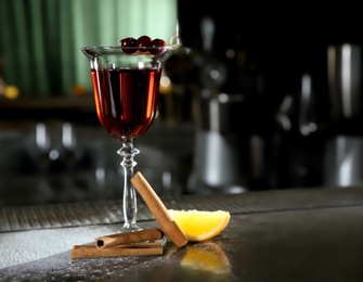 Photo of Fresh red cinnamon whiskey alcoholic cocktail on bar counter. Space for text