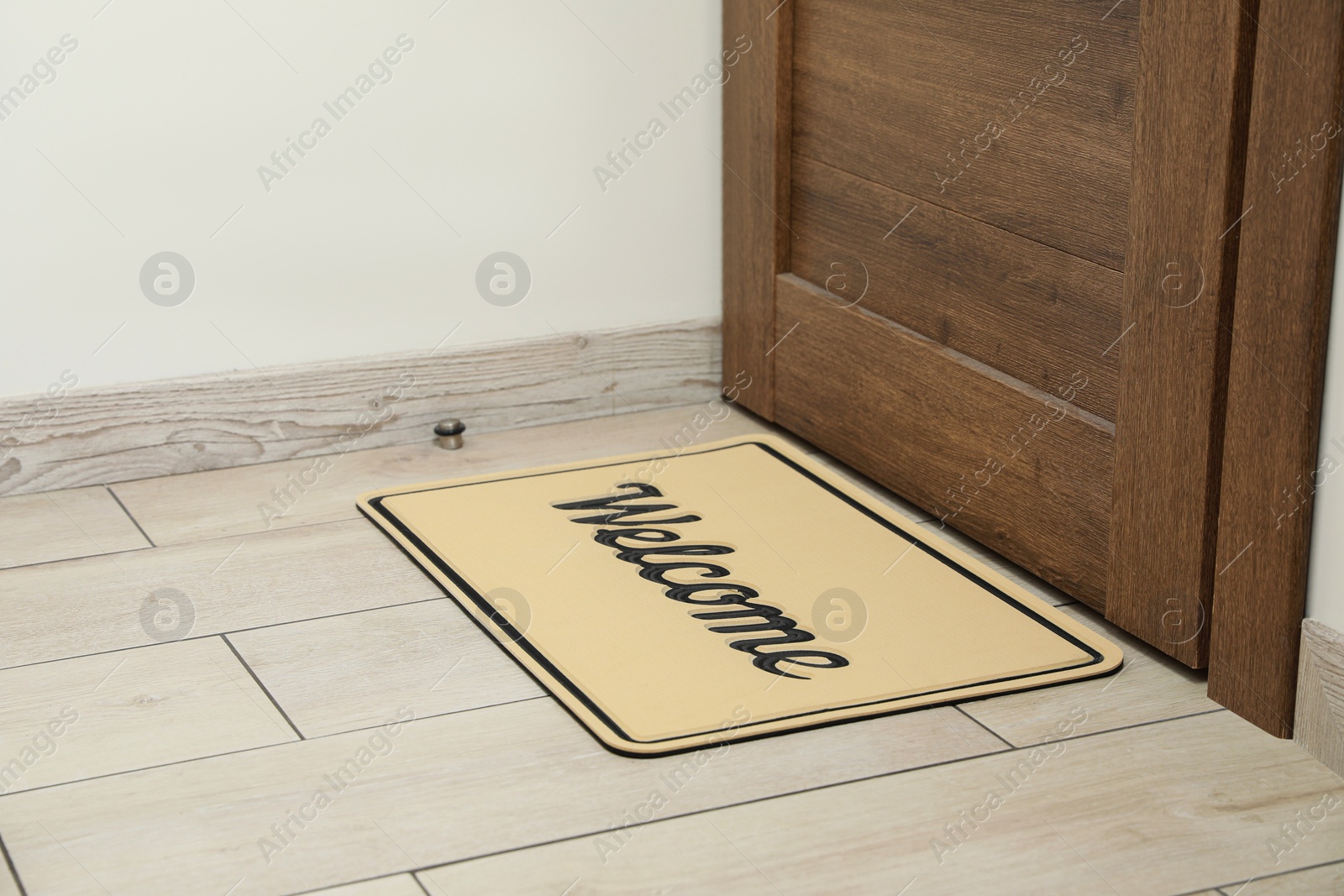 Photo of Beautiful beige doormat with word Welcome on floor near entrance