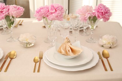 Stylish table setting with beautiful peonies and fabric napkin indoors