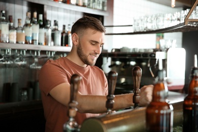 Photo of Bartender working at beer tap in pub