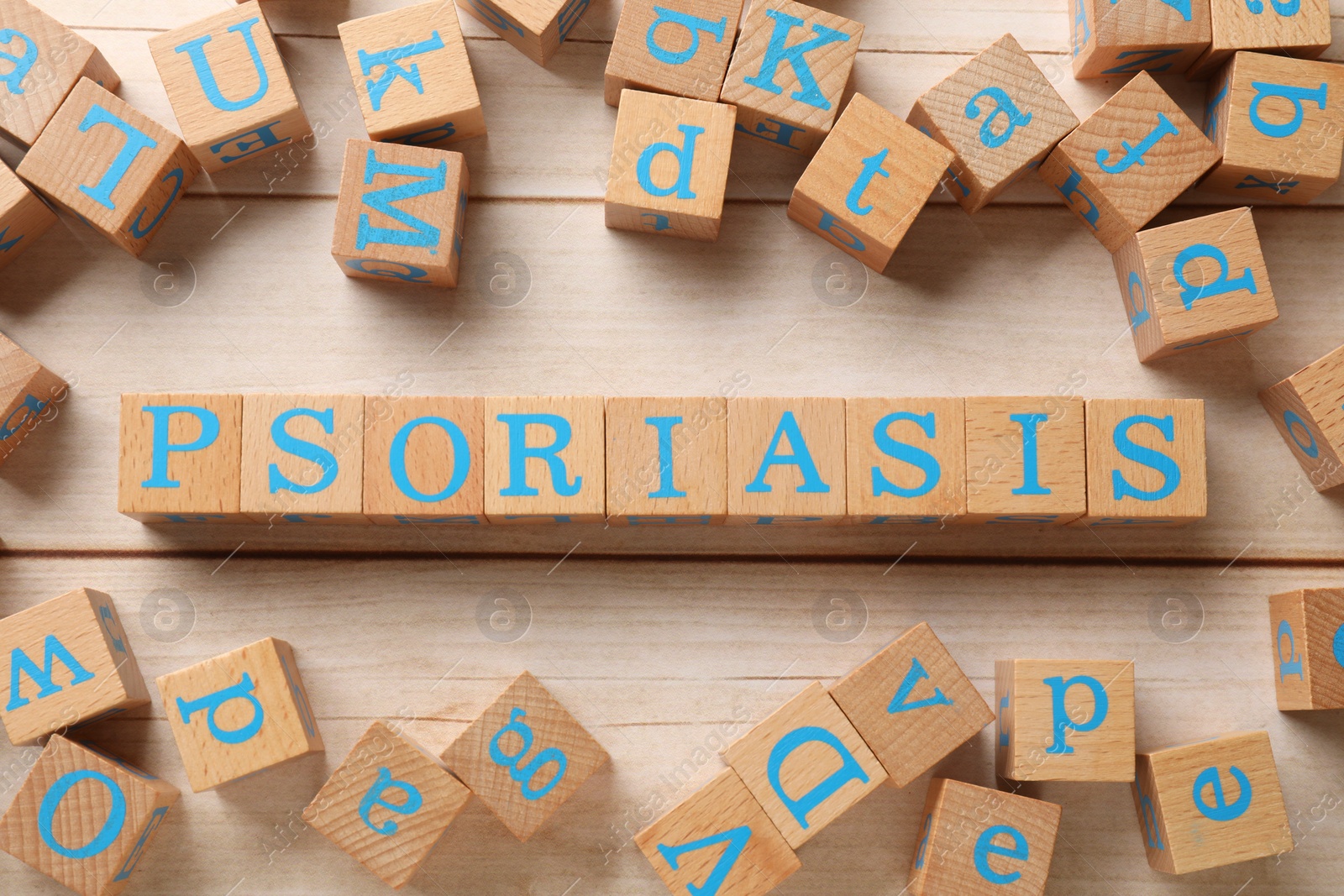 Photo of Word Psoriasis made of cubes with letters on white wooden table, flat lay