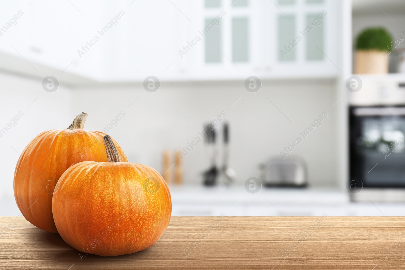 Image of Fresh pumpkins on wooden table in kitchen. Space for text