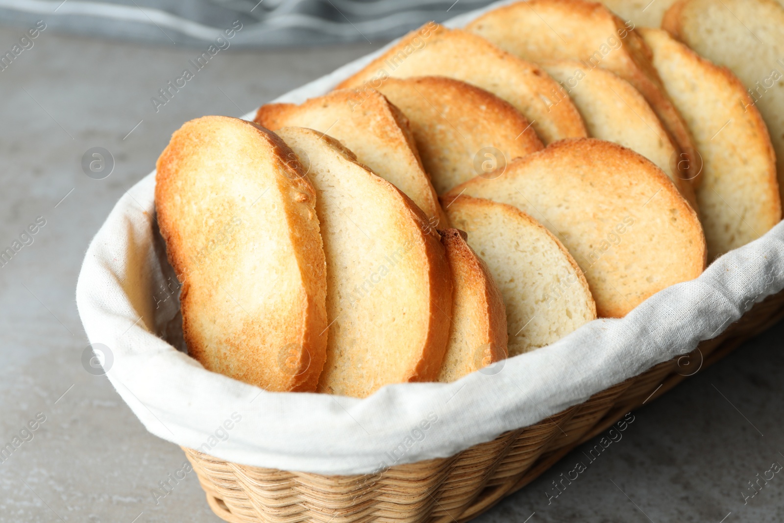 Photo of Slices of toasted bread in basket on grey table