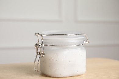 Jar of salt scrub on wooden table
