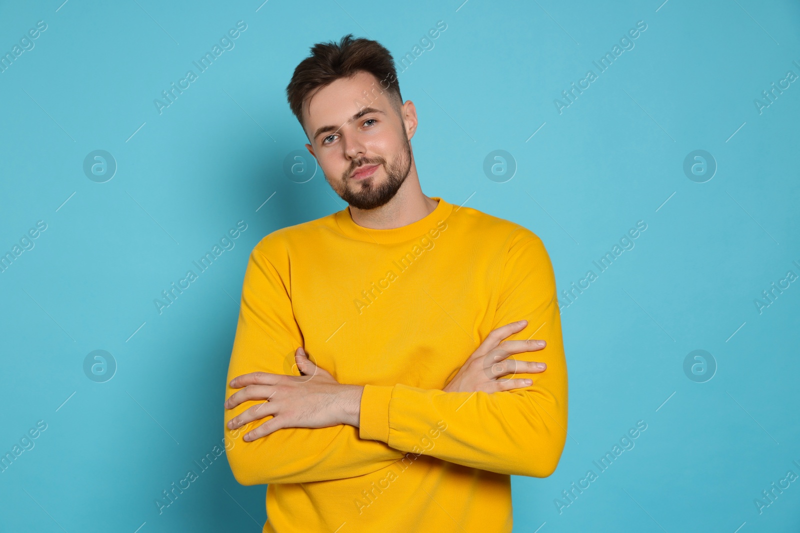 Photo of Handsome man in yellow sweatshirt on light blue background