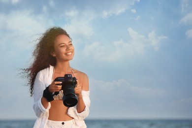 African American photographer with professional camera near sea