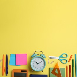 Image of Flat lay composition with alarm clock and different stationery on yellow background, space for text