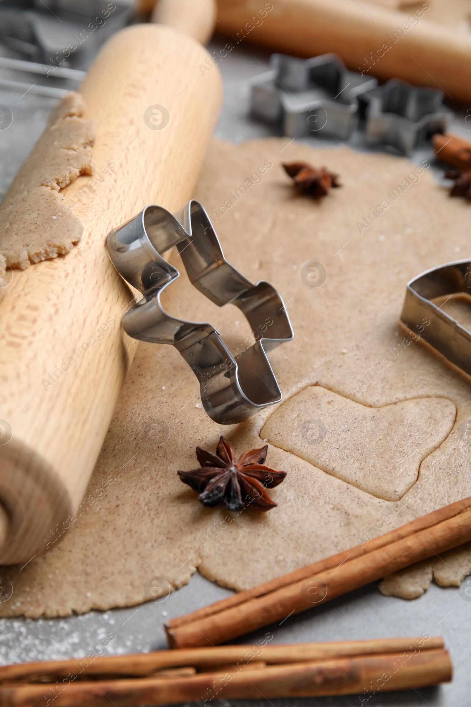 Photo of Homemade Christmas biscuits. Raw dough, rolling pin and cookie cutter on grey table, closeup