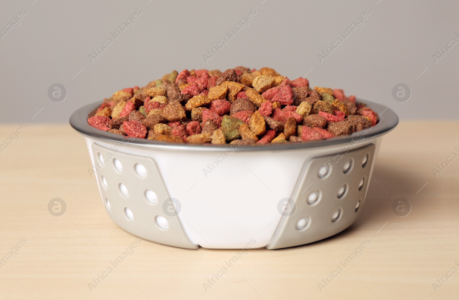 Photo of Dry dog food in pet bowl on wooden surface