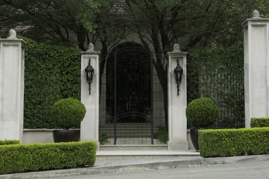 Beautiful stone fence with ornate black metal gates around house and garden