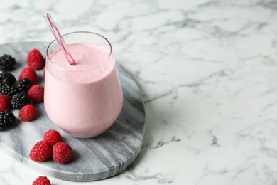 Yummy berry smoothie in glass on white marble table, space for text 