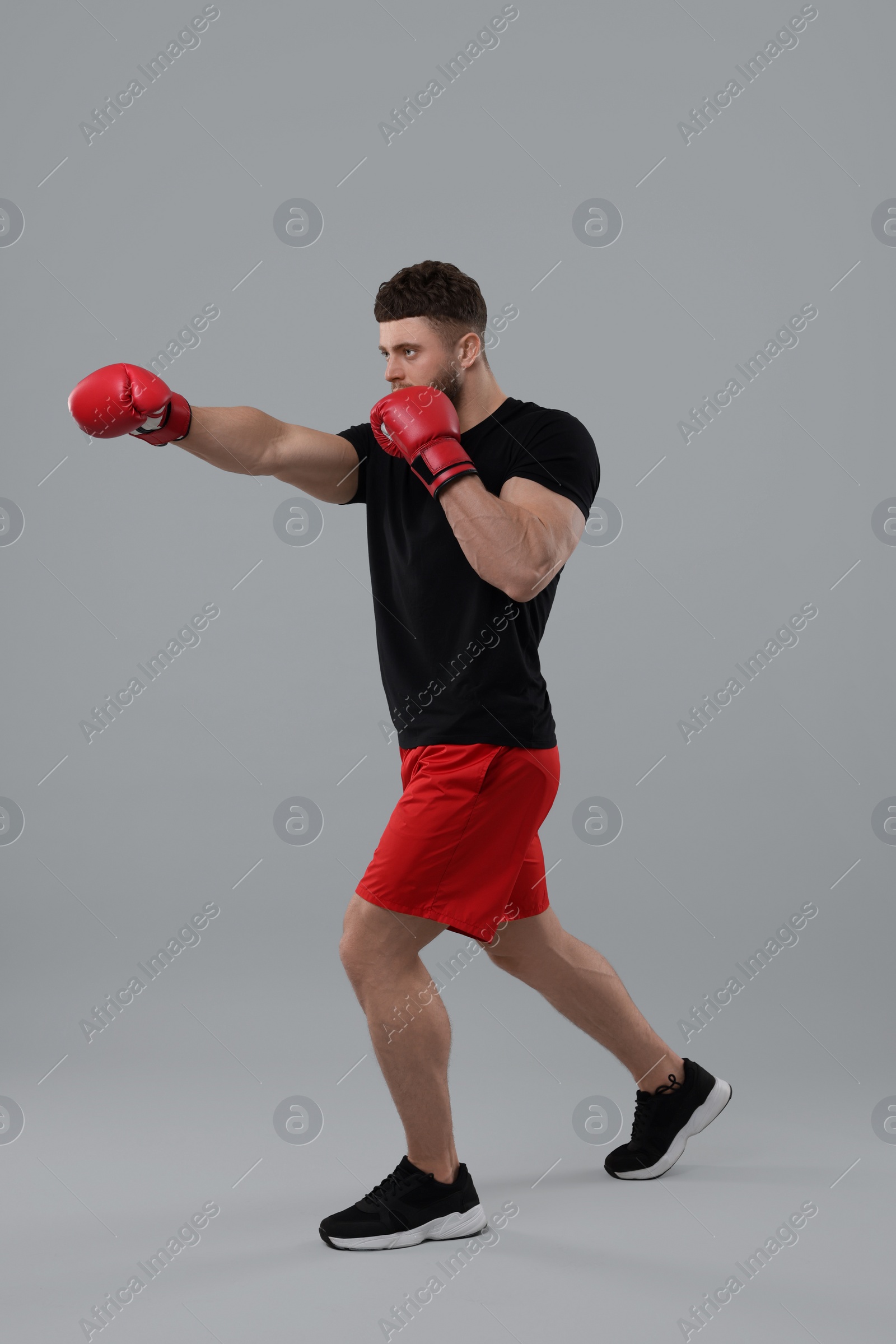 Photo of Man in boxing gloves fighting on grey background