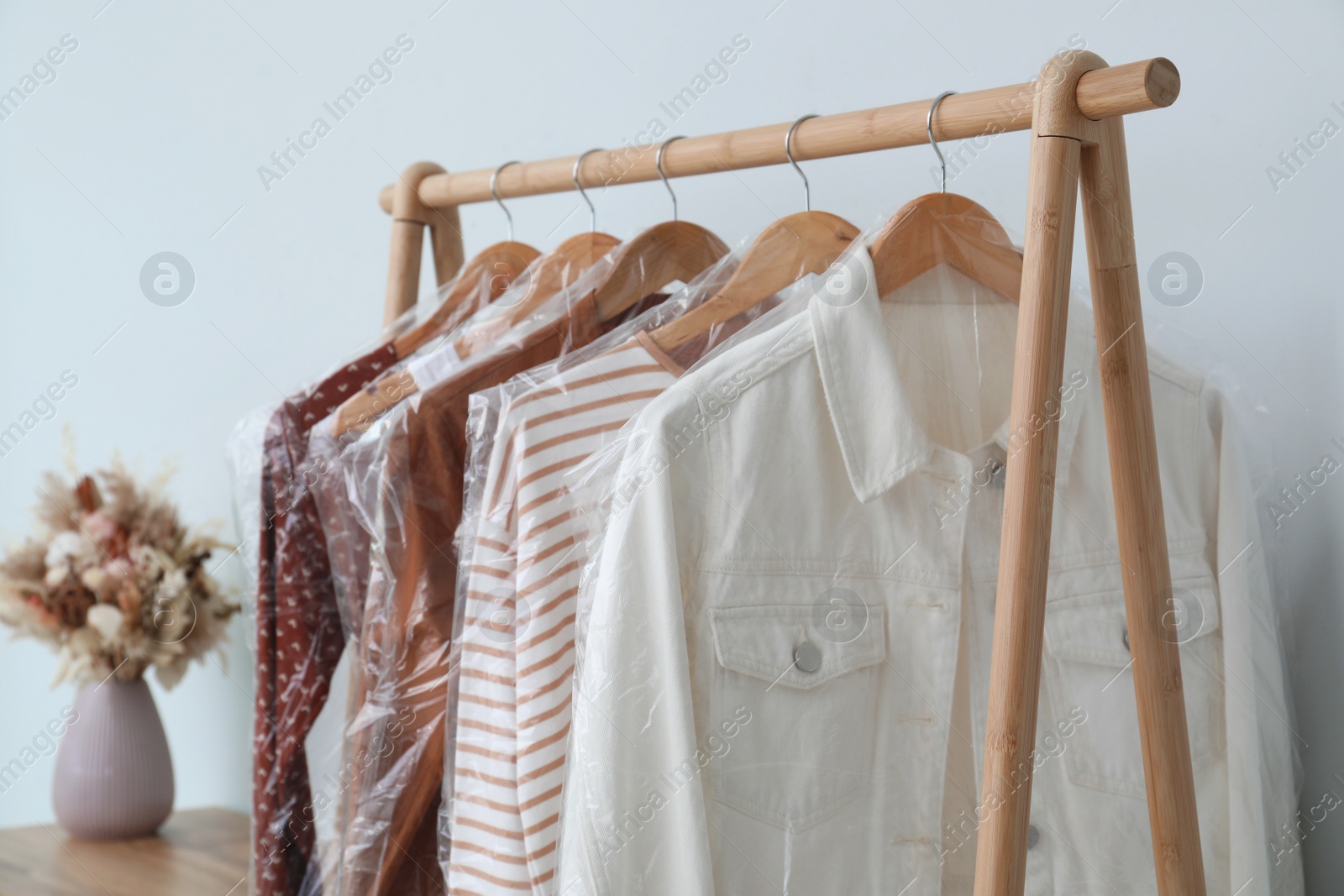 Photo of Rack with clothes in plastic bags indoors