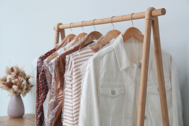 Photo of Rack with clothes in plastic bags indoors