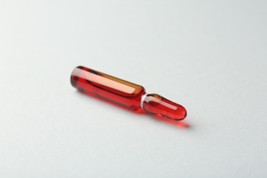 Glass ampoule with liquid on white background