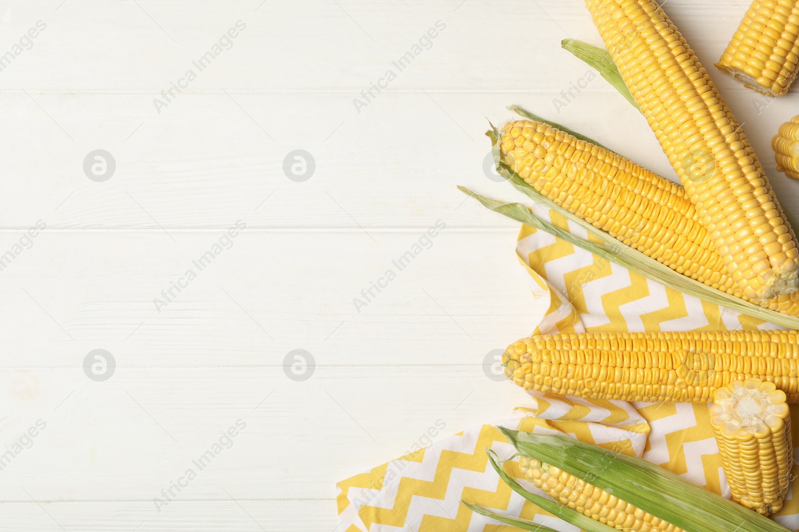 Photo of Corn cobs on white wooden table, flat lay. Space for text