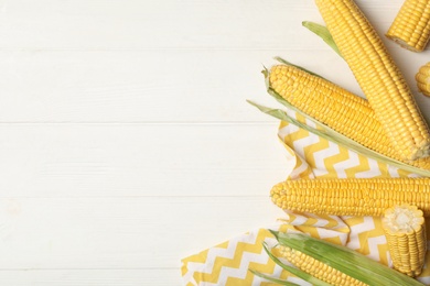 Photo of Corn cobs on white wooden table, flat lay. Space for text