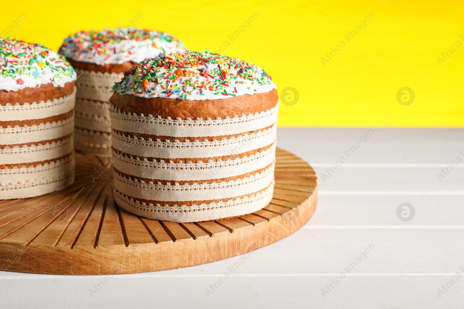 Photo of Traditional Easter cakes with sprinkles on white wooden table. Space for text