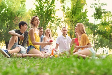 Photo of Happy friends having picnic in park on sunny day