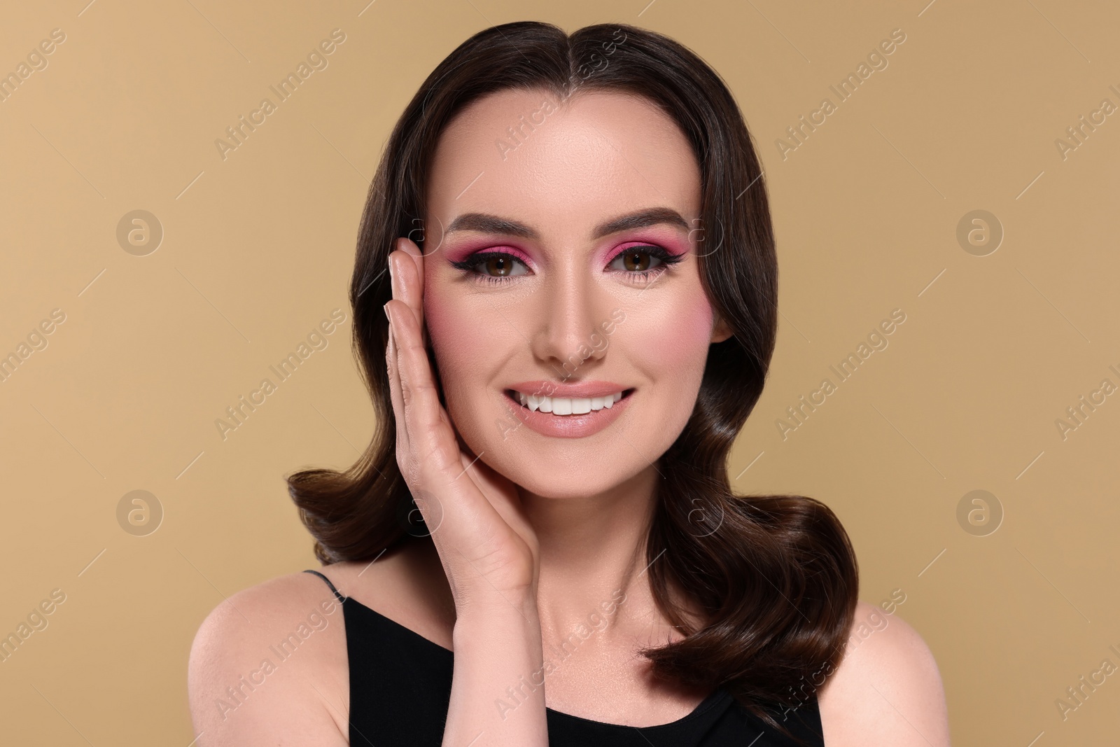 Photo of Portrait of beautiful young woman with makeup and gorgeous hair styling on beige background