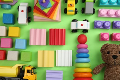 Different children's toys on green background, flat lay