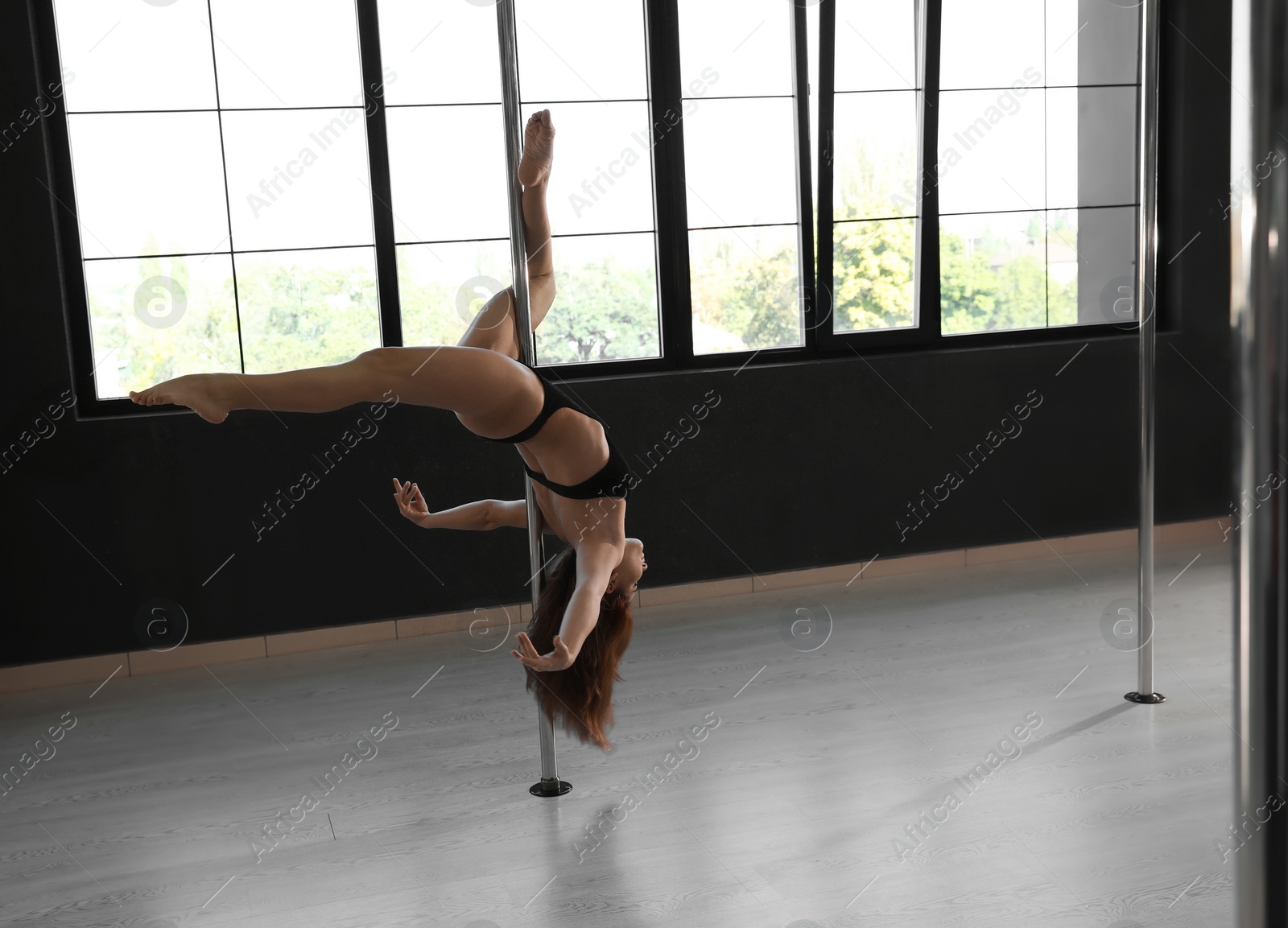 Photo of Beautiful young woman dancing in studio with poles