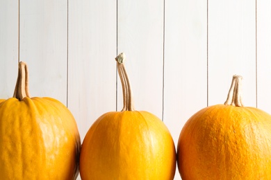 Photo of Ripe pumpkins against light wooden background. Holiday decoration