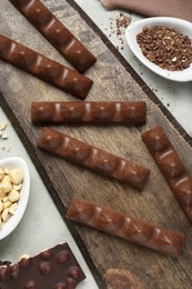 Photo of Tasty chocolate bars and nuts on light grey table, flat lay