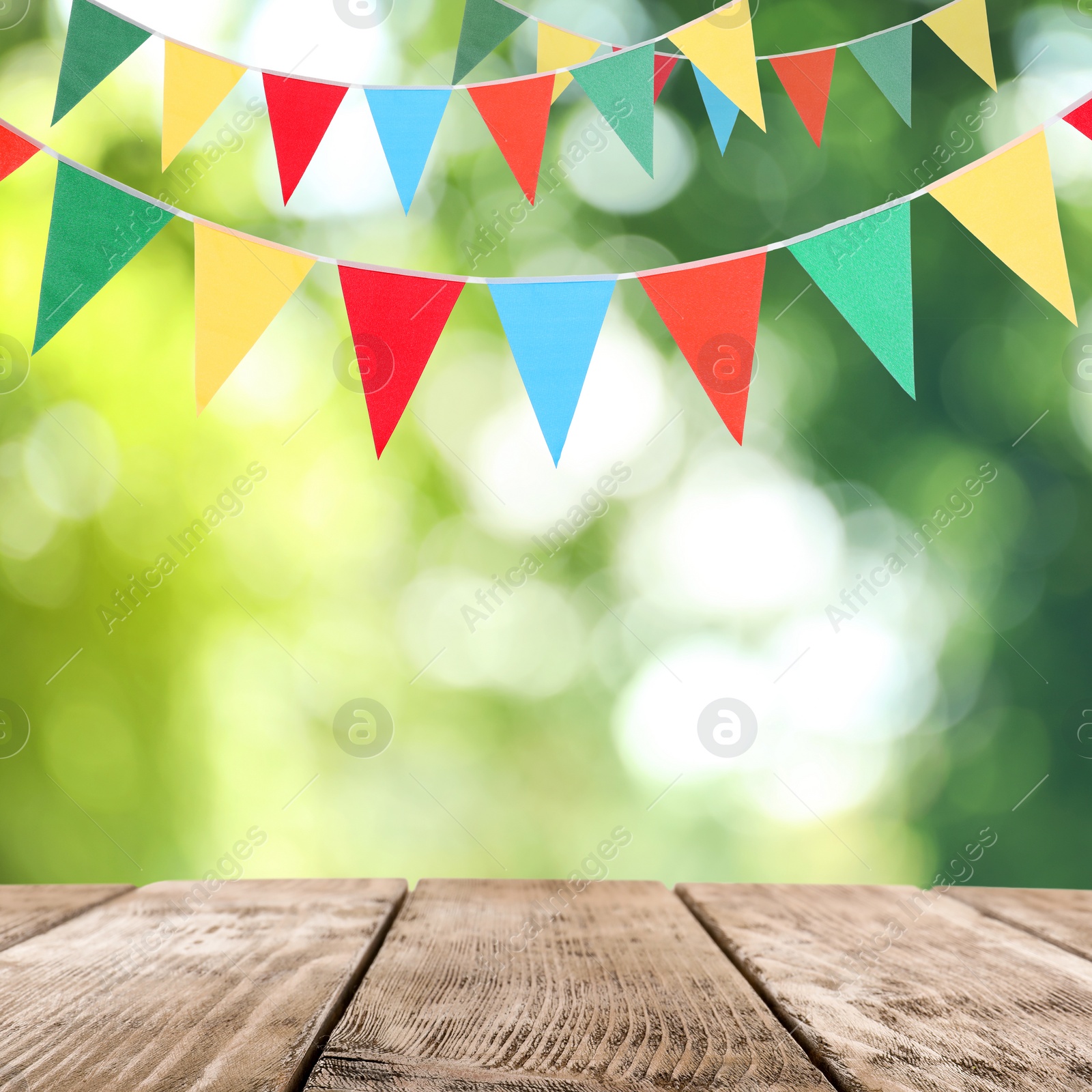 Image of Empty wooden table and decorative bunting flags outdoors