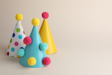 Colorful party hats with pompoms on beige background. Space for text