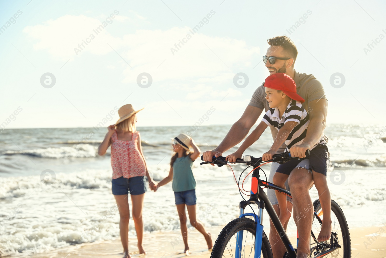 Photo of Happy family with bicycle on sandy beach near sea