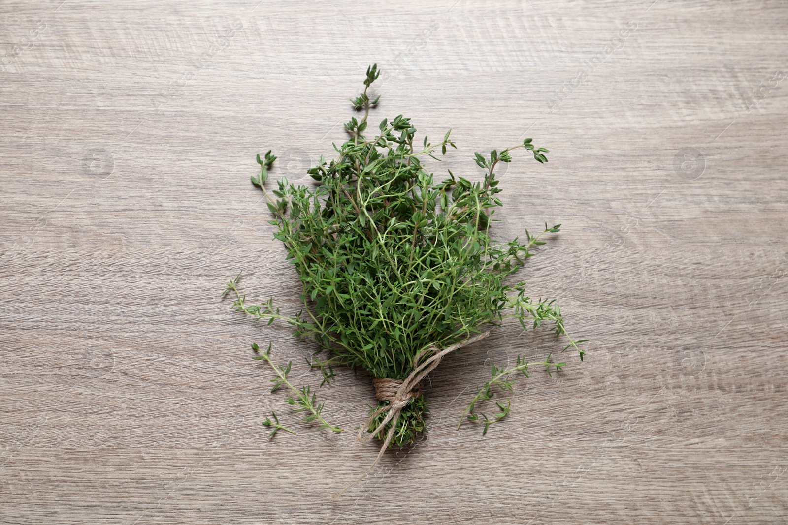 Photo of Bunch of aromatic thyme on wooden table, top view