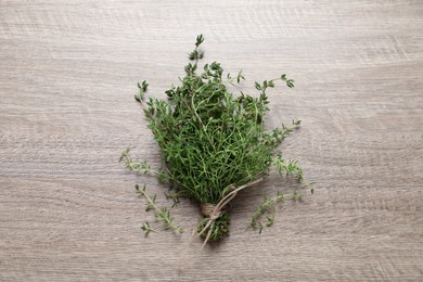 Photo of Bunch of aromatic thyme on wooden table, top view