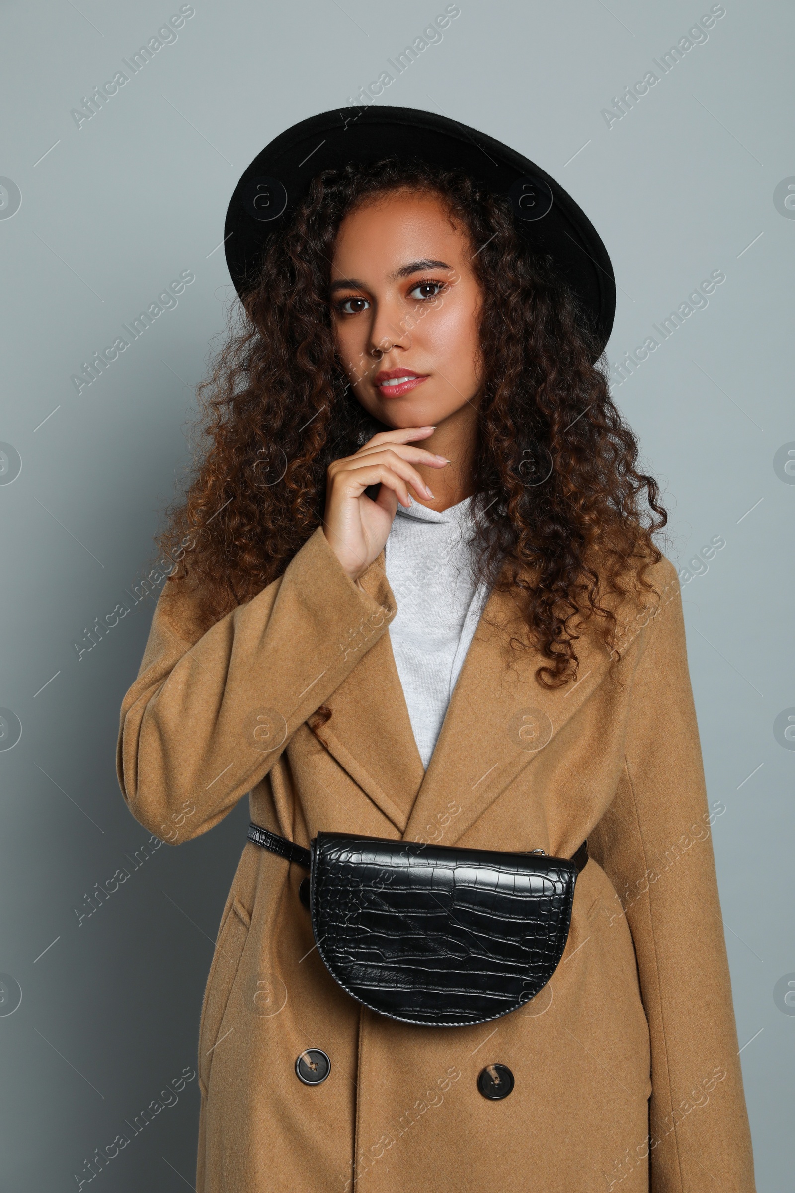 Photo of Beautiful African American woman with stylish waist bag on grey background