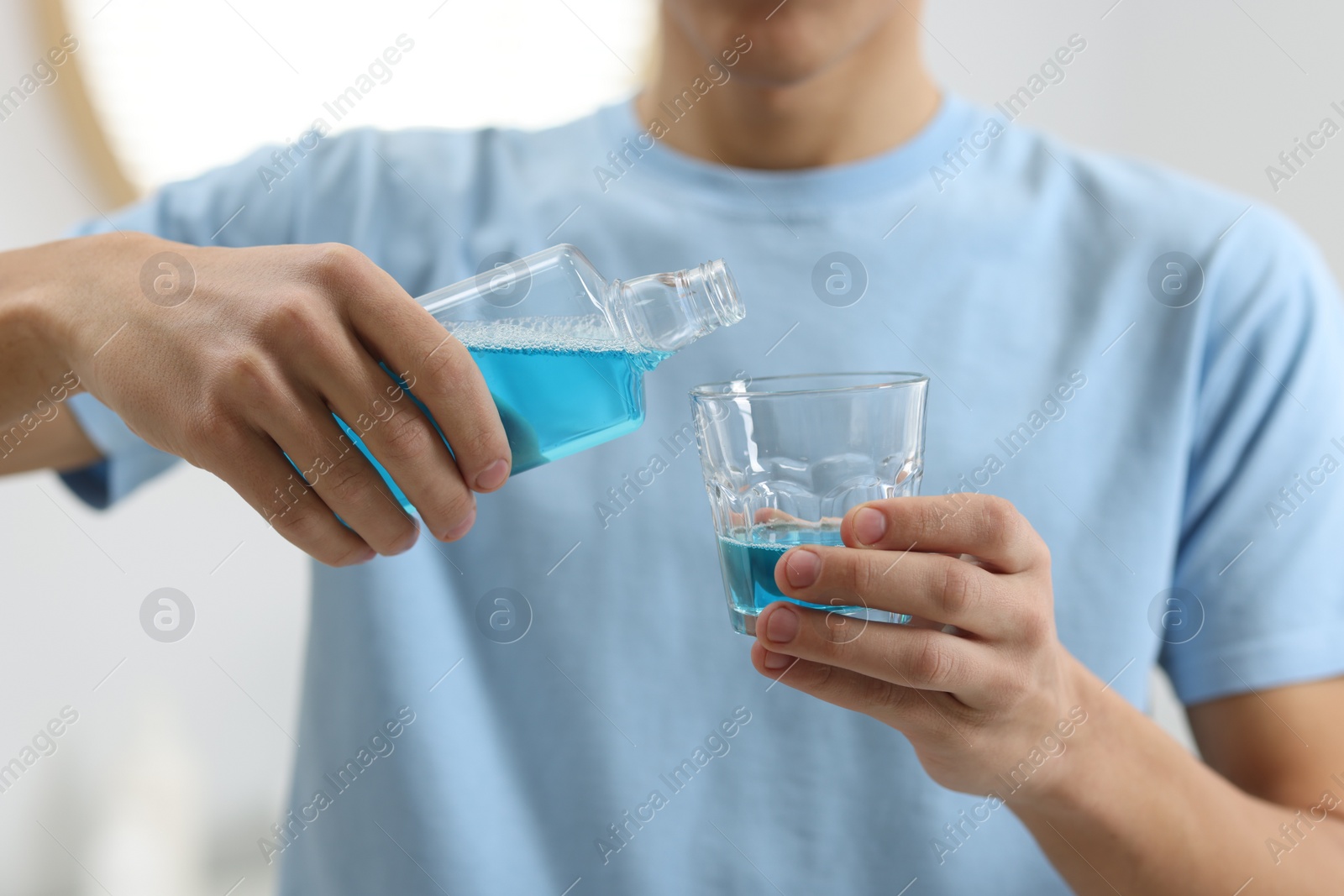 Photo of Young man using mouthwash indoors, closeup view