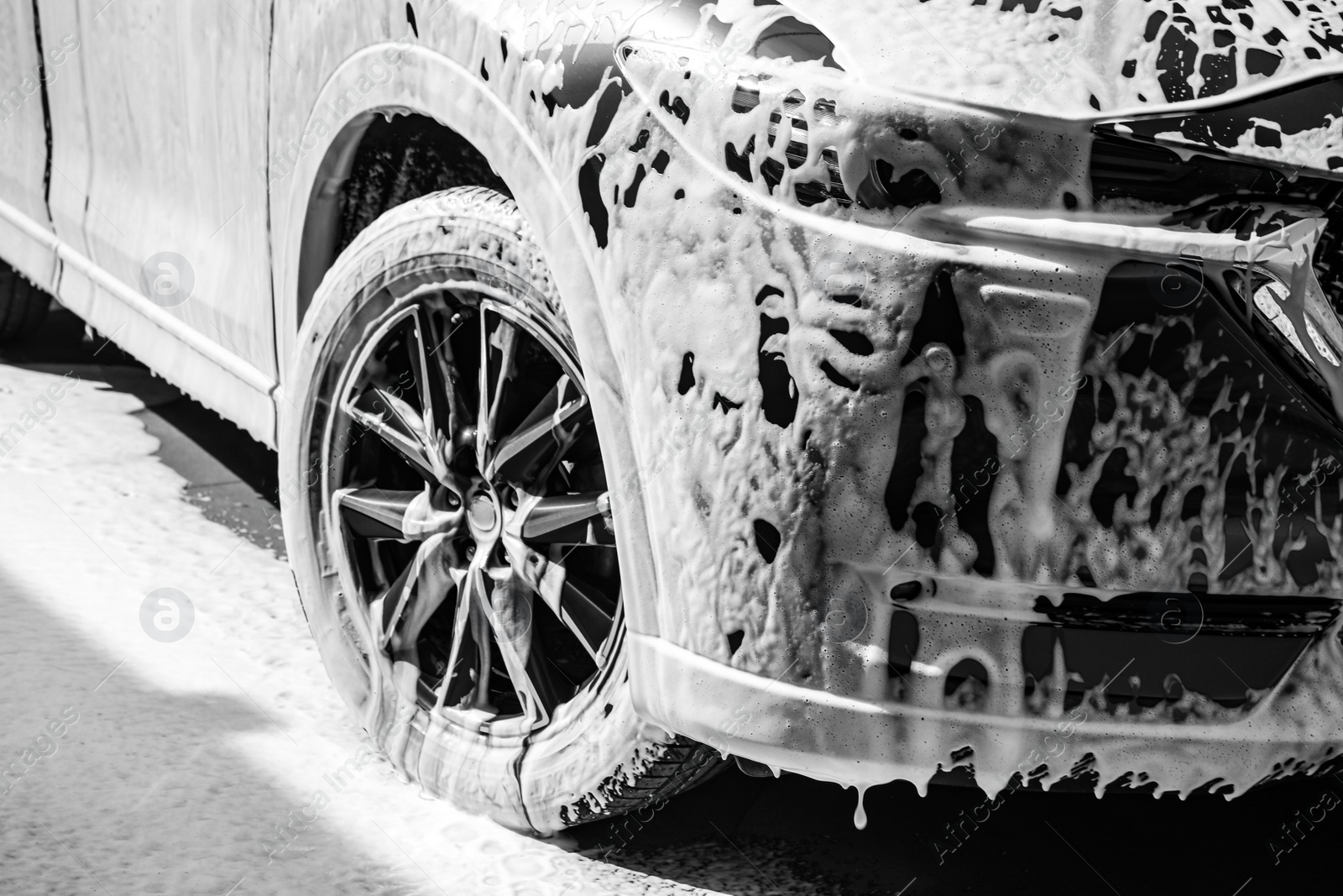 Photo of Luxury automobile covered with foam at car wash, closeup