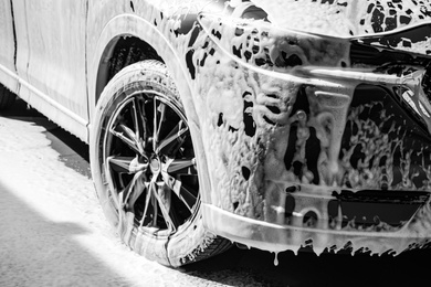 Luxury automobile covered with foam at car wash, closeup