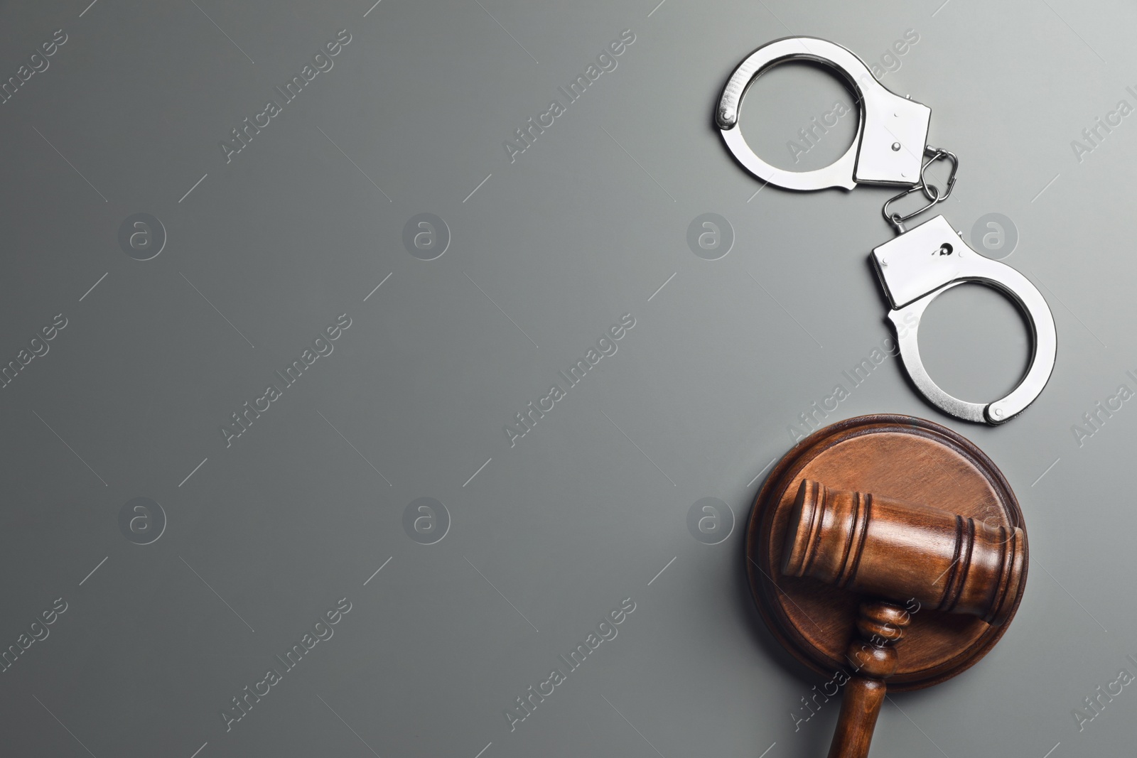 Photo of Judge's gavel and handcuffs on grey background, flat lay with space for text. Criminal law concept