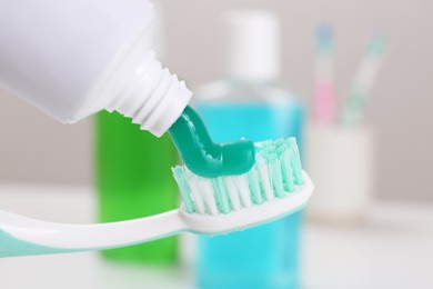 Photo of Applying paste on toothbrush near mouthwash, closeup