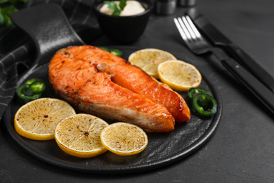 Photo of Delicious roasted fish served on black table