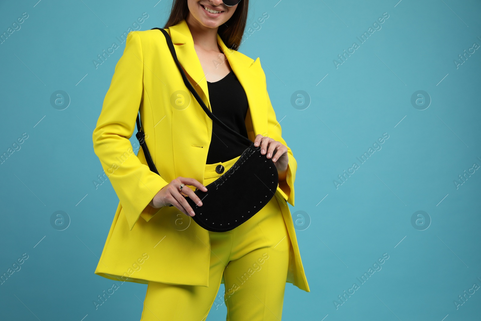 Photo of Fashionable young woman with stylish bag on light blue background, closeup. Space for text