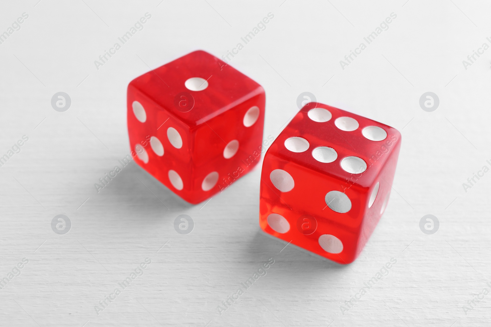 Photo of Two red game dices on white wooden table, closeup